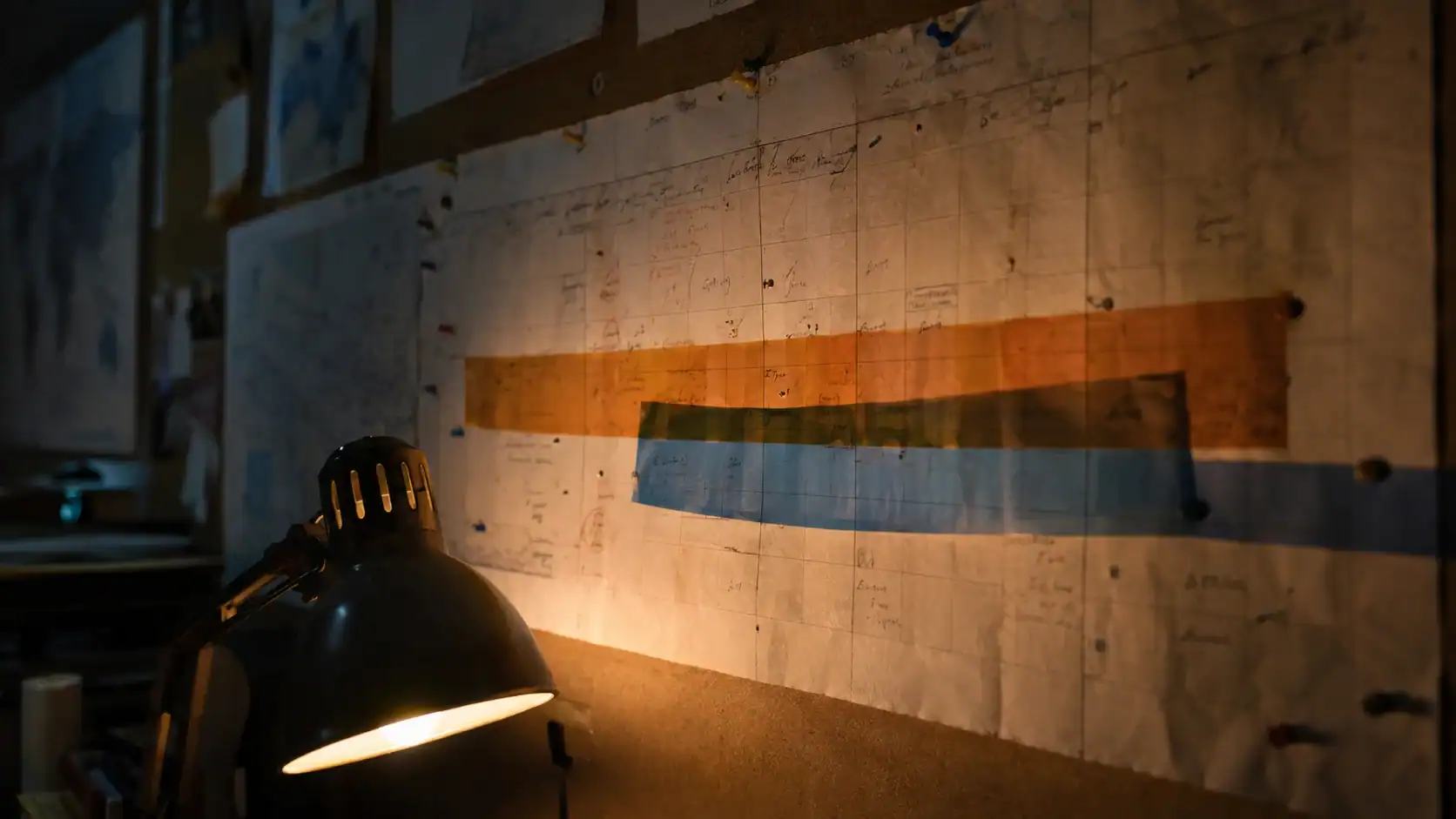Overlapping orange and blue risk-window bands illuminated across a hand-marked calendar chart pinned to a corkboard, representing layered seasonal shipping risk periods for Australia